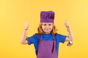 Wall Mural - Funny kid chef cook with kitchen ladle, studio portrait. Kid in cooker uniform and chef hat preparing food on studio color background. Cooking, culinary and kids food concept.