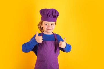 Wall Mural - Cooking children. Chef kid boy making healthy food. Portrait of little child in chef hat isolated on studio background. Kid chef. Cooking process.