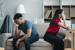 Unhappy young couple sitting apart, having problems in relationship, thinking of breaking up or divorce, upset, family lovers, man and woman avoid talking in relationship problems.