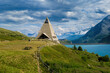 View of the modern pyramid shaped church, alpine lake of Mont-Cenis and mountains on background in France.