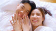 Top view young couple two asia people lying down on bed fun video phone call relax smile look at webcam camera talk show ring on hand finger. Sweet lover asian man woman on family day love life begin.