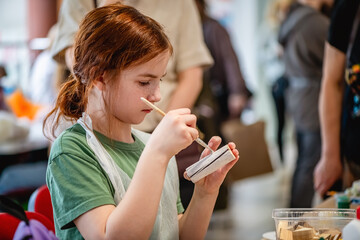 cute teen girl at a master class making a craft from wood, exhibition of crafts, crafts fair, education, master classes