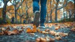 A person walking through an urban park, kicking up fallen leaves as they stroll