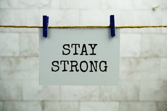 Stay Strong text on paper card hanging on the wall with Clothespins