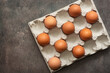 Brown eggs in a cardboard box. Top view, flat lay. Dark background.