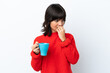 Young caucasian woman holding cup of coffee isolated on white background having doubts