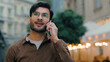 Successful confident happy Indian Arabian ethnic man male student guy businessman talking mobile phone cellphone conversation speaking communication business call connection outdoors walk city street