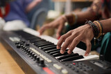 Hand of young unrecognizable male musician pressing keys of electronic synthesizer while composing, performing and recording his music