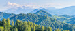 Panoramic mountain view. Spring landscape, green forests and snow-capped mountain peaks.