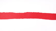 torn white sheet of paper with rough edges revealing red background with copy space
