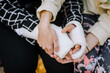 A caring woman, mother, girlfriend holds hands in a cast, bandage an injured sick girl, a child after a bone fracture, cares with help. Close-up photography, portrait, rehabilitation.