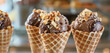 Gelato cones served with a sprinkle of crushed nuts and chocolate.