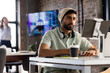 © Wavebreak Media - Asian male professional wearing headphones sitting at desk, looking at tablet in a modern business o