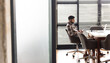 © Wavebreak Media - Asian young professional man sitting alone at a conference table in a modern business office, lookin