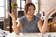 © Wavebreak Media - Asian woman sitting at desk in a modern business office, looking happy and gesturing with hands on v