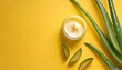 Cream with aloe vera gel and pieces of aloe on yellow background. Flat lay. Empty advertising banner template for cosmetics