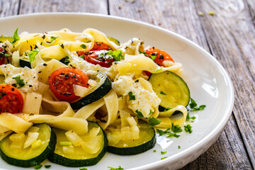 Wall Mural - Pappardelle with parmesan, zucchini, tomato and cream sauce on wooden table

