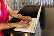 © Wavebreak Media - Indian woman wearing pink clothing typing on laptop at home