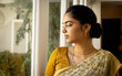 © Wavebreak Media - Indian young woman wearing traditional saree, looking out window at home