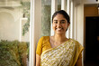 © Wavebreak Media - Indian young woman wearing yellow sari, smiling at home near window