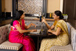 © Wavebreak Media - Indian mother and daughter in traditional attire with laptop at home table