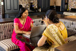 © Wavebreak Media - Indian mother and teenage daughter wearing sarees, viewing laptop and smartphone