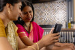 © Wavebreak Media - Indian mother and teenage teenage daughter in Indian saree view a smartphone at home
