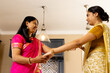© Wavebreak Media - Indian mother in pink saree and teenage daughter in yellow saree exchanging something at home