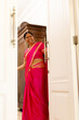 © Wavebreak Media - A middle-aged Indian woman wearing bright pink sari, opening a door at home