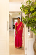 © Wavebreak Media - A mature Indian woman wearing bright pink saree standing at home