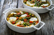 Bread casserole with green asparagus, goat cheese, tomatoes and eggs on wooden table

