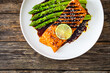 Grilled salmon steak with green asparagus in teriyaki sauce on wooden table

