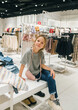 Young Girl Smiling While Sitting in a Modern Clothing Store