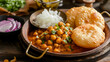 A delightful plate of chole bhature, with spicy and tangy chickpea curry served with fluffy deep-fried bread called bhature, garnished with pickles and onions.