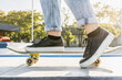 © oneinchpunch - Young female skateboarder at skate park, close-up on shoes