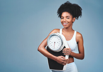 Wall Mural - Black girl, portrait and scale in studio to measure weight loss, confident and blue background. Female person, fitness and diet for balance, mockup space and proud of weightloss success and health