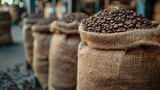 Fototapeta Uliczki - Roasted coffee beans overflow from open burlap sacks in a rustic warehouse, highlighting the richness and tradition of coffee roasting.