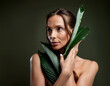 © Arda ALTAY - Depiction of a dreamy woman covering her upper body with exotic leaves on dark green yellow background