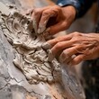Detailed view of an artist's hands as they carefully sculpt and add intricate textures to a piece of wet clay.
