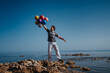 Young happy man with balloons on the shore of lake