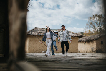 Wall Mural - A young woman leads two men along a wooden path in a historic village, laughing as they enjoy a vacation together.