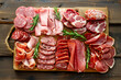 A wooden board with a variety of meats and vegetables, including ham, salami