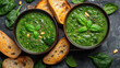 Green creamy spinach and broccoli soup with baguette toasts on a gray concrete background. Healthy food and diet. Top view.