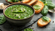 Green creamy spinach and broccoli soup with baguette toasts on a gray concrete background. Healthy food and diet. Top view.