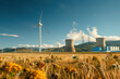 A low-angle shot showing a power station and a wind turbine, highlighting the coexistence of traditional and renewable energy sources.

