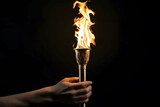 Fototapeta  - Closeup, Hand holding Olympic Games fire torch isolated on black background