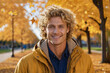 Portrait of a smiling blond man with blue eyes in an autumn park in sunny weather