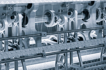 Leinwandbilder - A machine is weaving a fabric with many different colored threads. The machine is blue and white