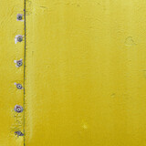 Fototapeta Dmuchawce - Vintage metallic board. Yellow color template frame, old metal door surface with screws.