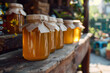 Jars of homemade honey lined up on a wooden stall in a garden